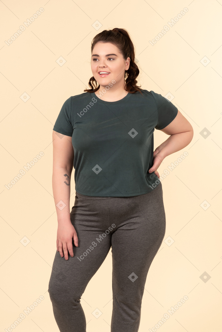 Young plus size woman in sport clothes standing against a pastel yellow background