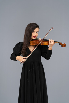 Close-up de uma jovem de vestido preto tocando violino