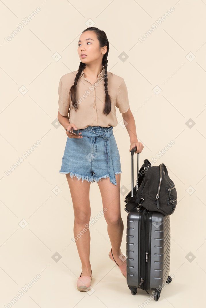 Молодая женщина с чемоданом смотрит в сторону