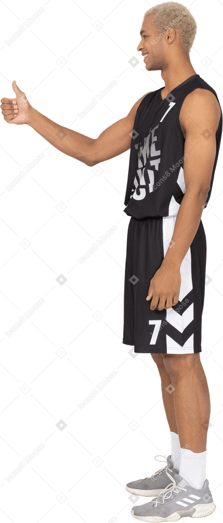 Vista laterale di un giovane giocatore di basket maschile che mostra il pollice in su