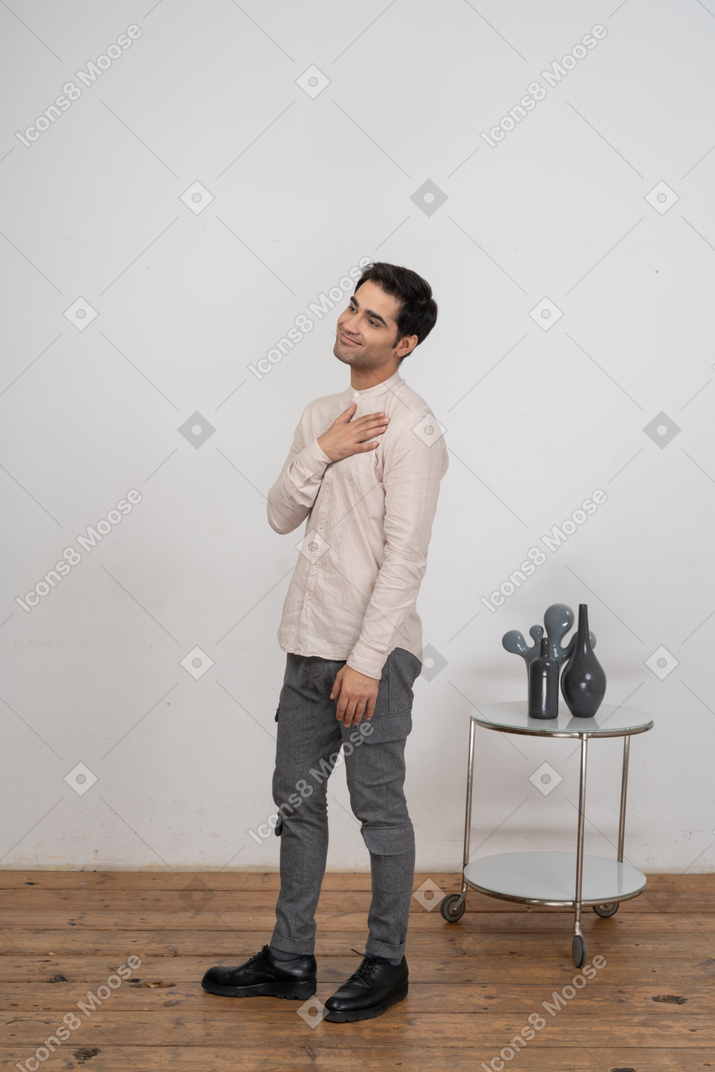 Vista lateral de um homem com roupas casuais, posando com a mão no peito