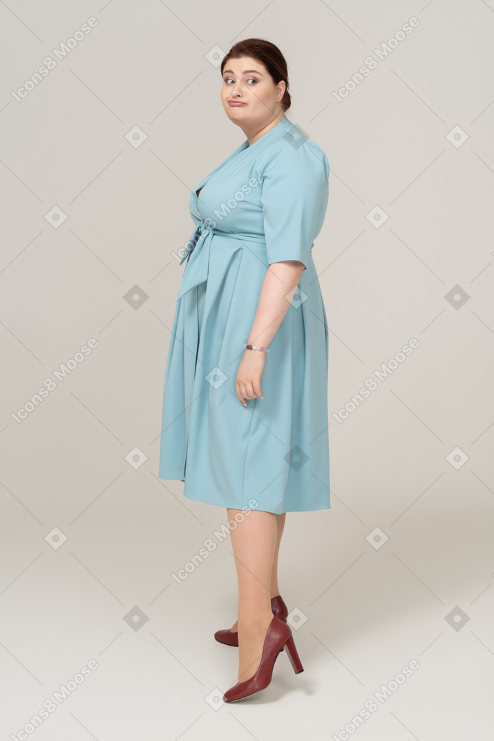 一个穿着蓝色裙子的女人看着相机和做鬼脸的侧视图