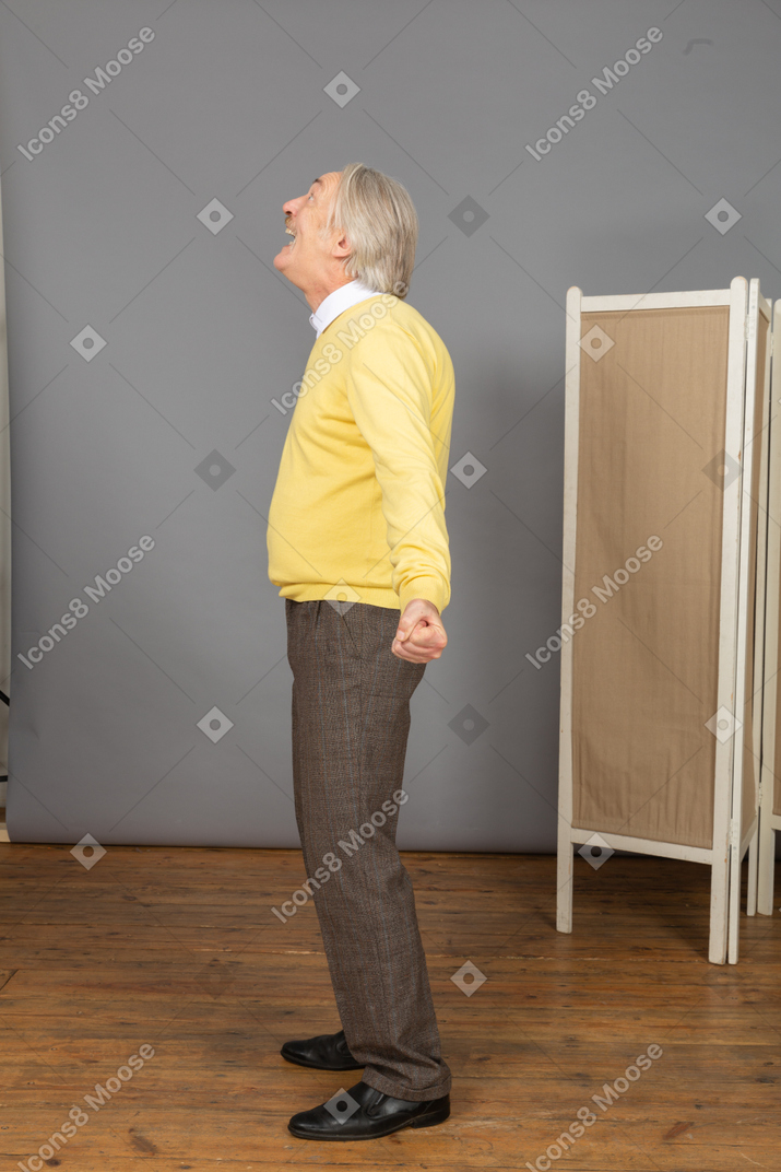 Side view of a screaming old man outspreading hands while looking up