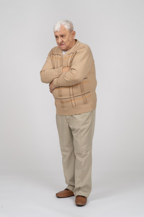 Vista frontal de un anciano con ropa informal de pie con los brazos cruzados