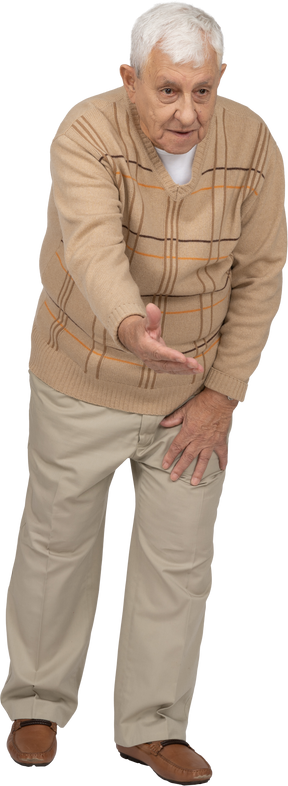 Front view of an old man in casual clothes standing with outstretched arm and explaining something