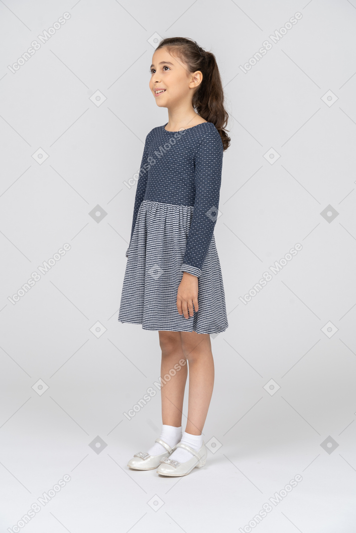 Vista de tres cuartos de una niña mirando hacia arriba con una sonrisa de ensueño