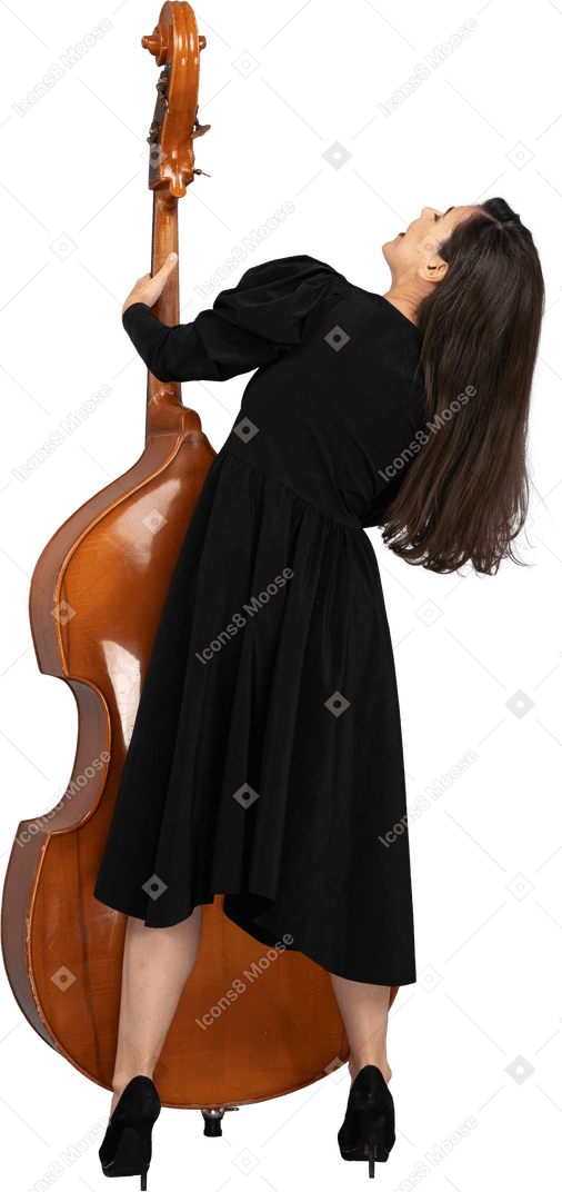 后面的观点的一位年轻的女音乐家，穿着黑色的连衣裙，抱着她的双低音