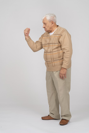 Vista laterale di un uomo anziano in abiti casual che mostra il pugno