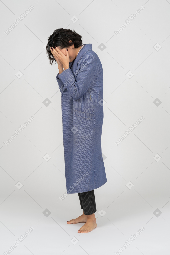 Upset woman in coat covering her face