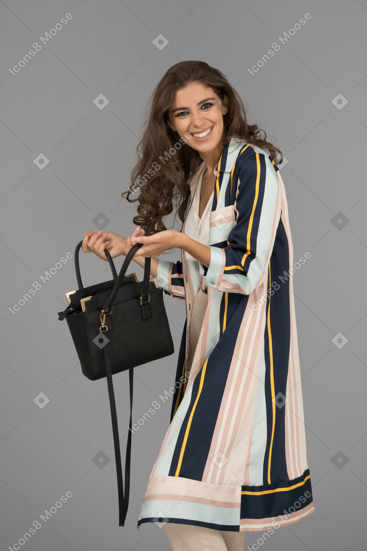 Happy attractive female with a black handbag facing camera