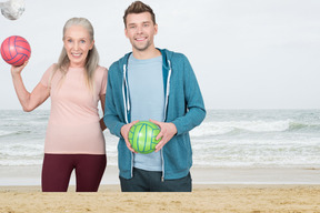 A man and a woman standing on a beach with a ball