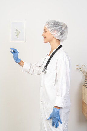 Side view of a young female doctor with stethoscope holding thermometer