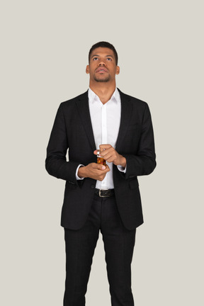 Pensive young man in black suit holding bottle of pills