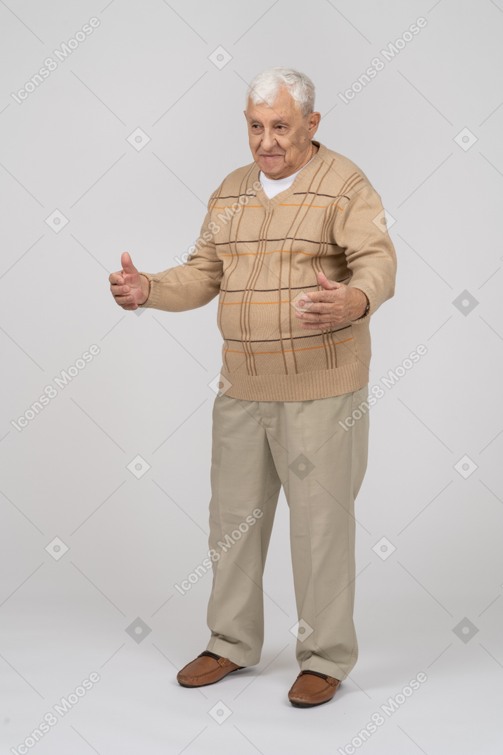 伸ばした腕で立っているカジュアルな服装で幸せな老人の正面図