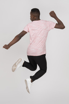 Back view of a young man jumping with folded legs