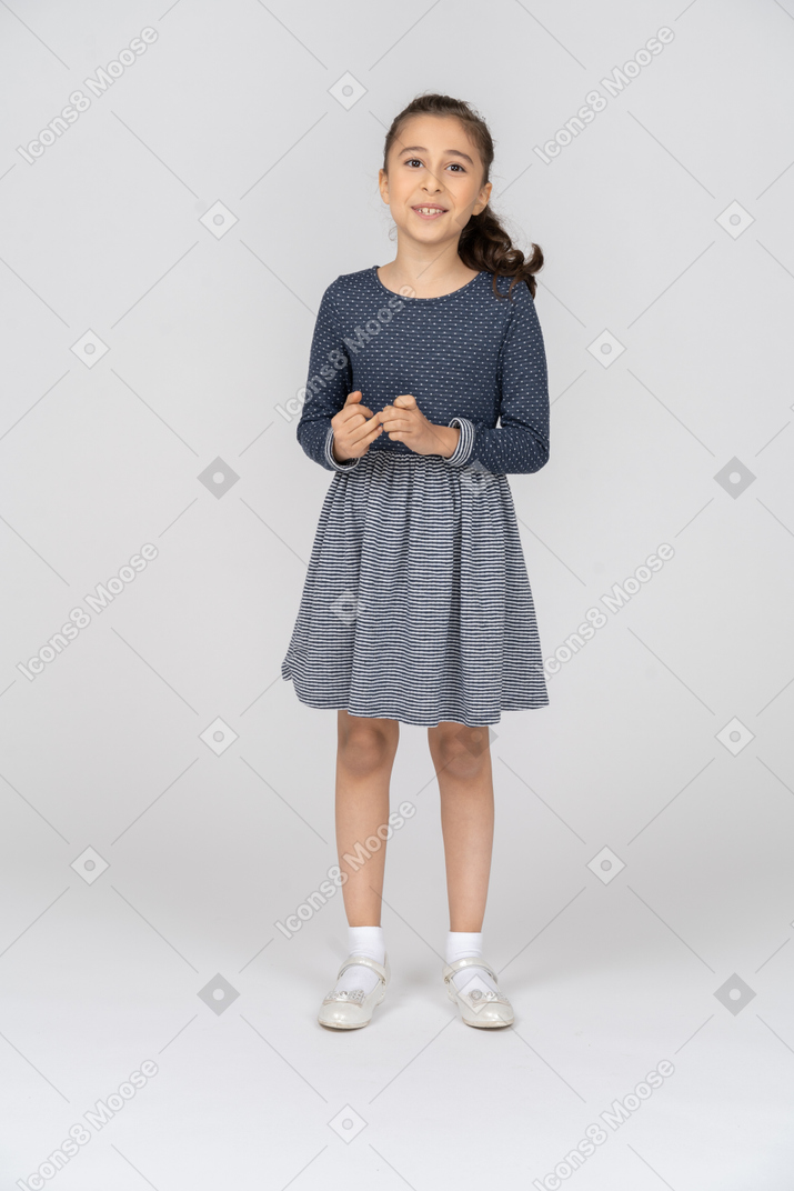 Vista frontal de uma garota brincando com os dedos e sorrindo alegremente