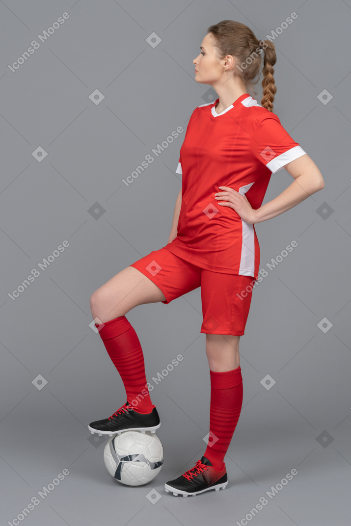 A sporty football player stepping on the ball