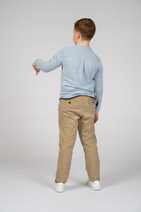 Rear view of a boy pointing down with finger