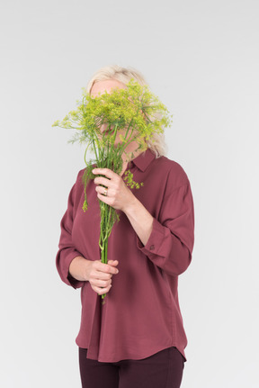 A nice-looking middle-aged blonde woman in a burgundy shirt and with a simple bouquet of flowers in her hands