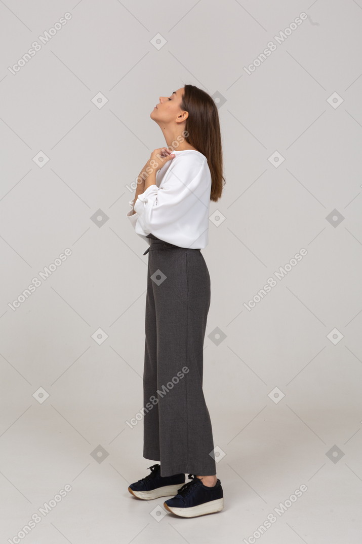 Side view of a young lady in office clothing adjusting her blouse