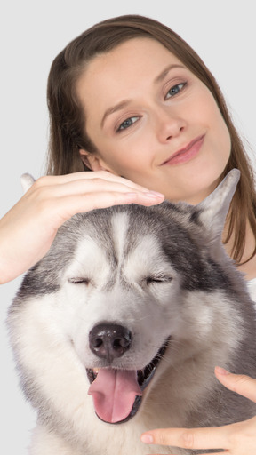 A woman is petting a husky dog