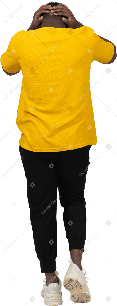 一个穿着黄色 t 恤、摸头的黑皮肤青年行走的后视图