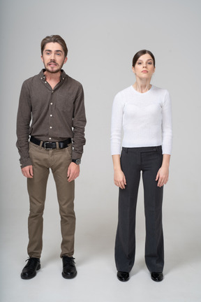 Front view of a young couple in office clothing raising head