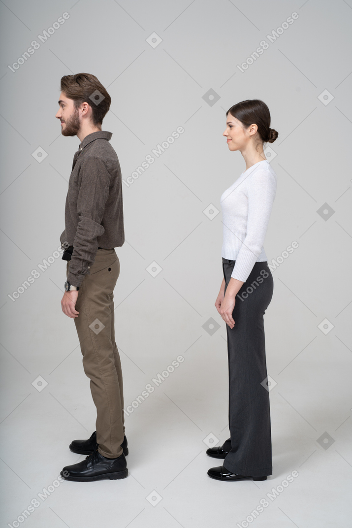 Vista lateral de um jovem casal satisfeito com roupas de escritório