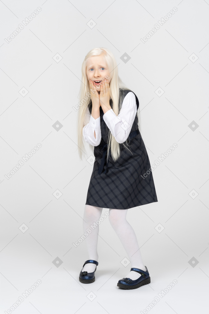 Schoolgirl touching her face, looking very scared