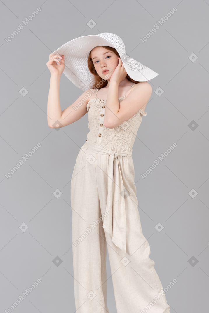 Teenage girl wearing big white hat and holding her hands in a pose