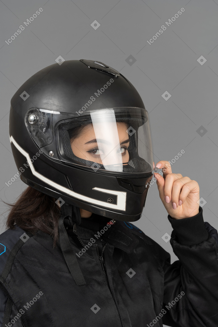 Um motociclista feminino fechando uma viseira de capacete
