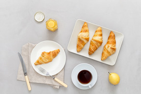 Some coffee, croissants, honey and a pear