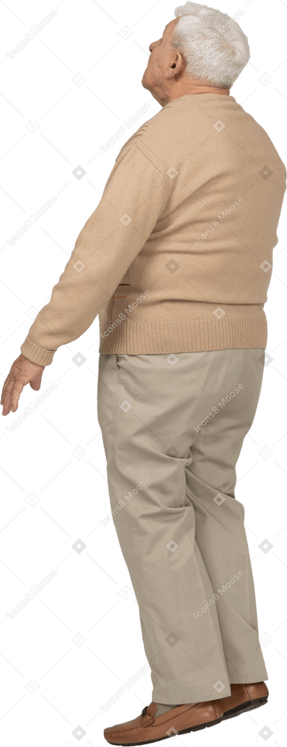 Vista lateral de un anciano con ropa informal de pie y mirando hacia arriba