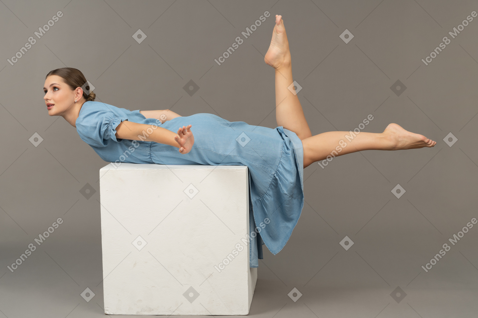 Side view of young woman lying on cube