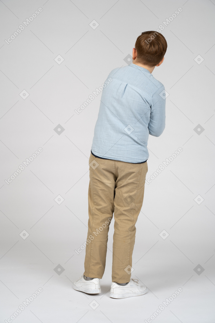 Мальчик стоит спиной к камере