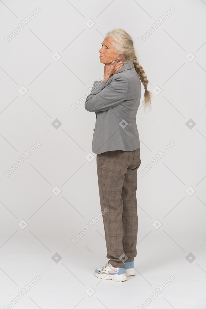 Side view of an old lady in suit touching her neck