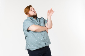 Pensive looking young overweight man standing with his hands crossed