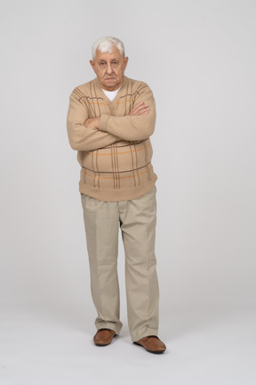 一位身穿休闲服的老人交叉双臂站着，看着相机的正面图