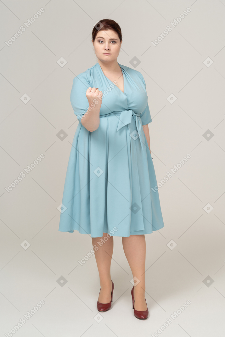 Vue de face d'une femme en robe bleue montrant le poing