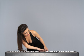 Front view of a young lady in black dress putting her hand on keyboard