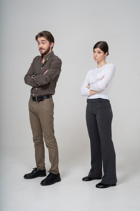 Three-quarter view of a young couple in office clothing crossing arms