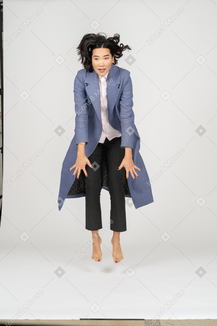 Woman in coat levitating barefoot