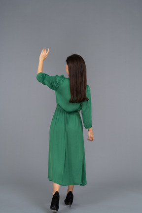 Back view of a greeting young lady in green dress