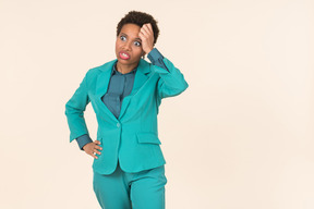 Black woman with a short haircut, wearing all blue, standing against a plain pastel background, looking emotional