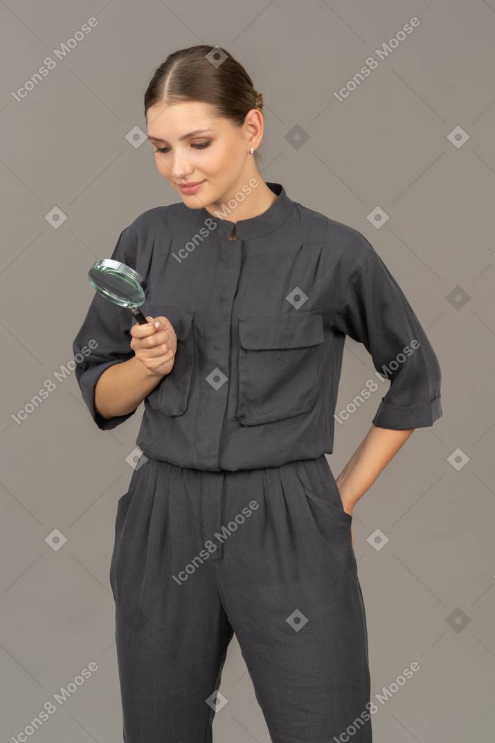 Vista frontale di una giovane donna in tuta con in mano una lente d'ingrandimento