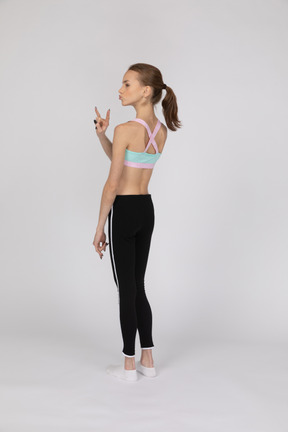 Teen girl in sportswear showing rock gesture