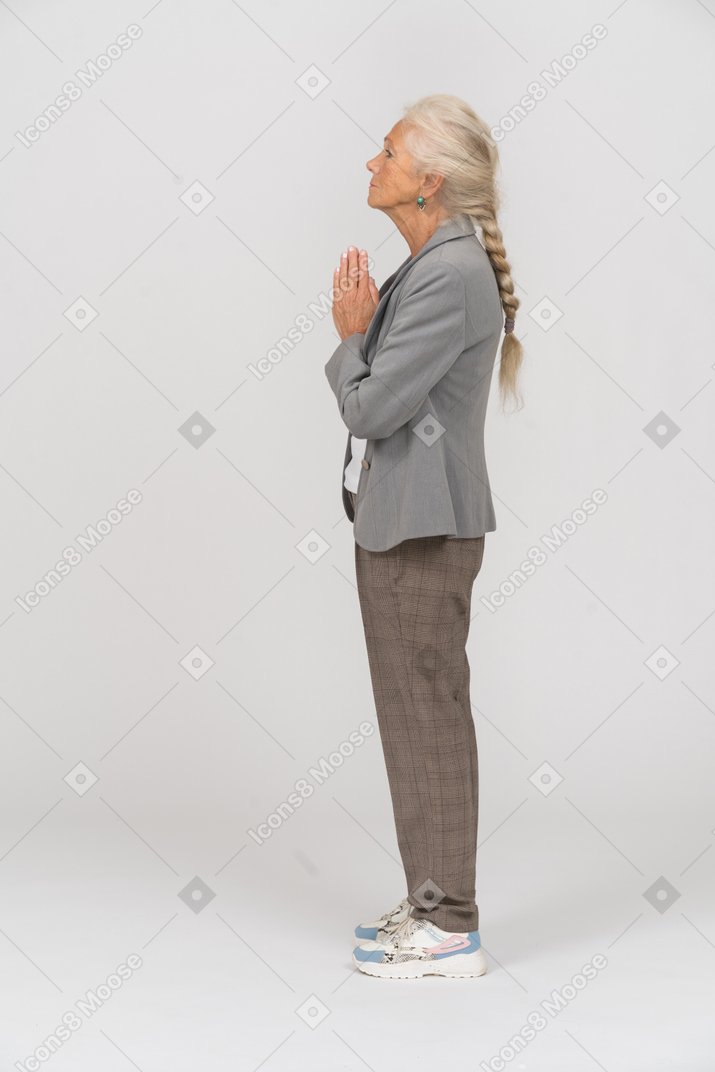Side view of an old lady in suit making praying gesture
