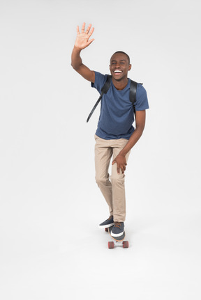 Smiling male tourist standing on skateboard and skating