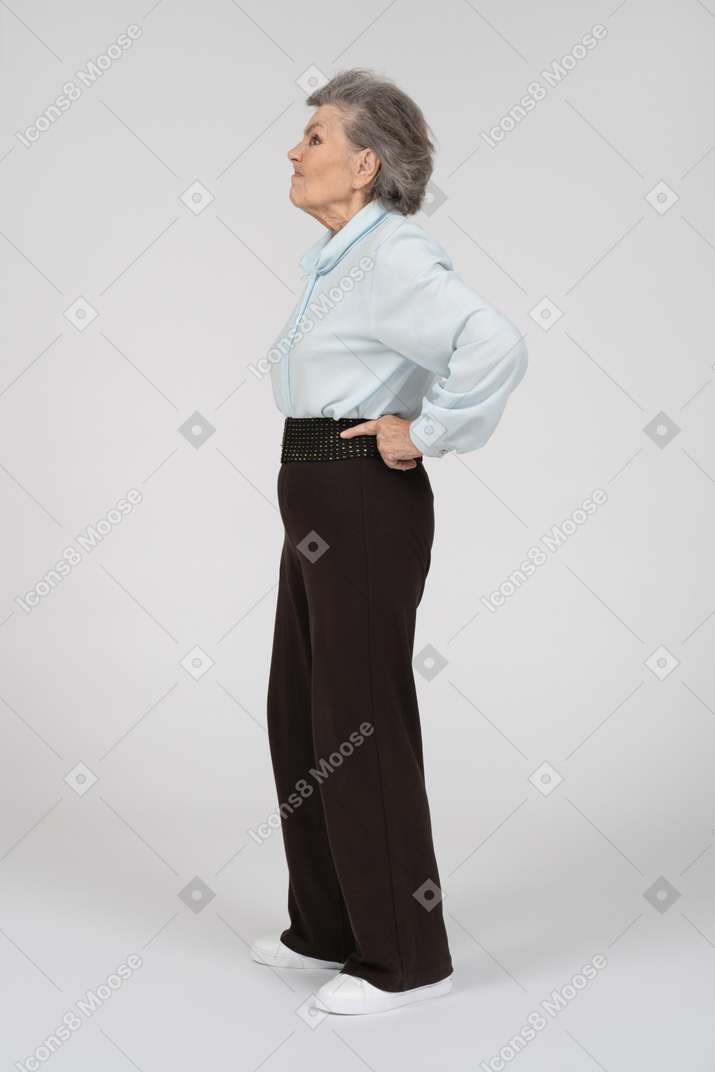 Вид сбоку пожилой женщины с руками на бедрах