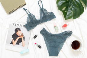 Lingerie di pizzo, tazza di caffè, rivista e foglia verde